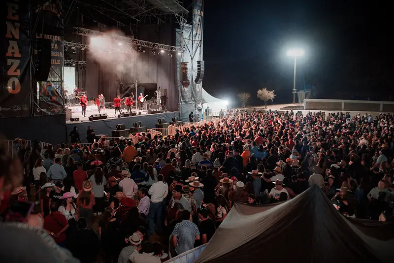 Banda en el escenario con luces y humo frente al público